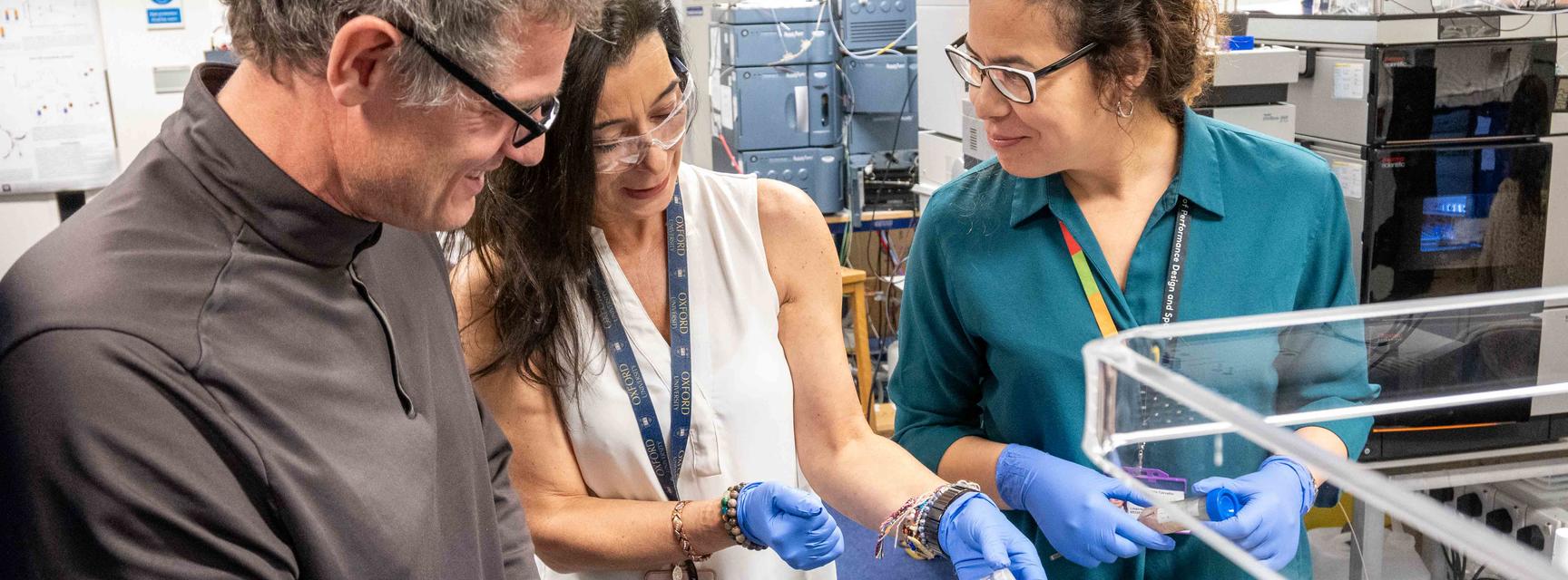 A group of three researchers look at a sample