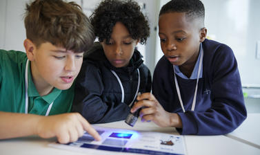 School students examining a printout of photos showing the effect of different dyes on identification of cell material
