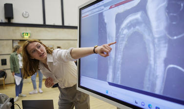 Researcher highlighting aspects of a tooth transect shown on a screen connected to a digital microscope 