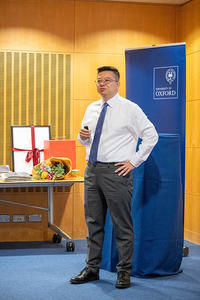 Dr Yingjian Andy Xu stands in front of the Oxford University crest at the launch of the XuPHOS Oxford Fund.